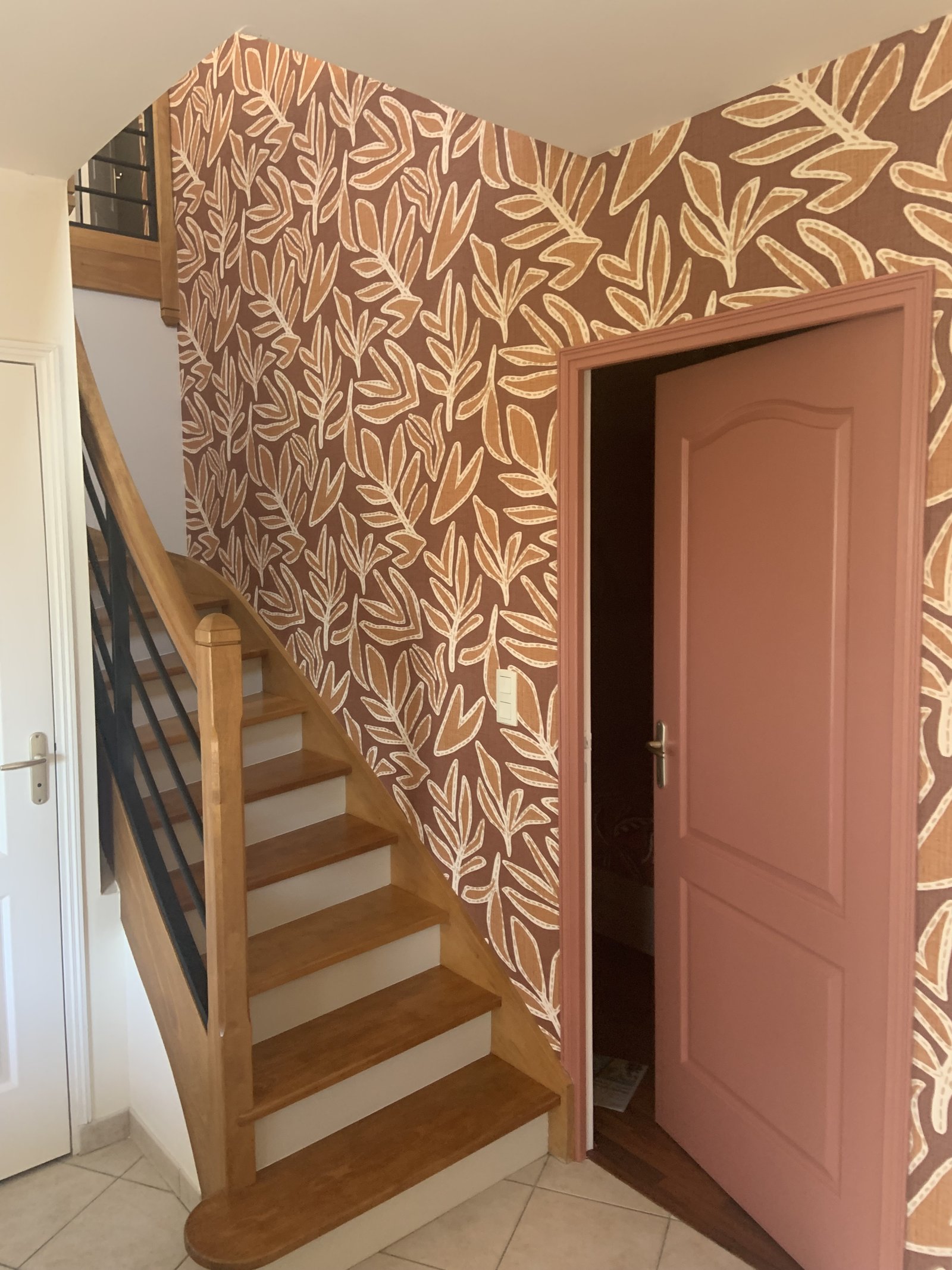 Cage d'escalier rénovée, papier peint terracotta et porte assortie